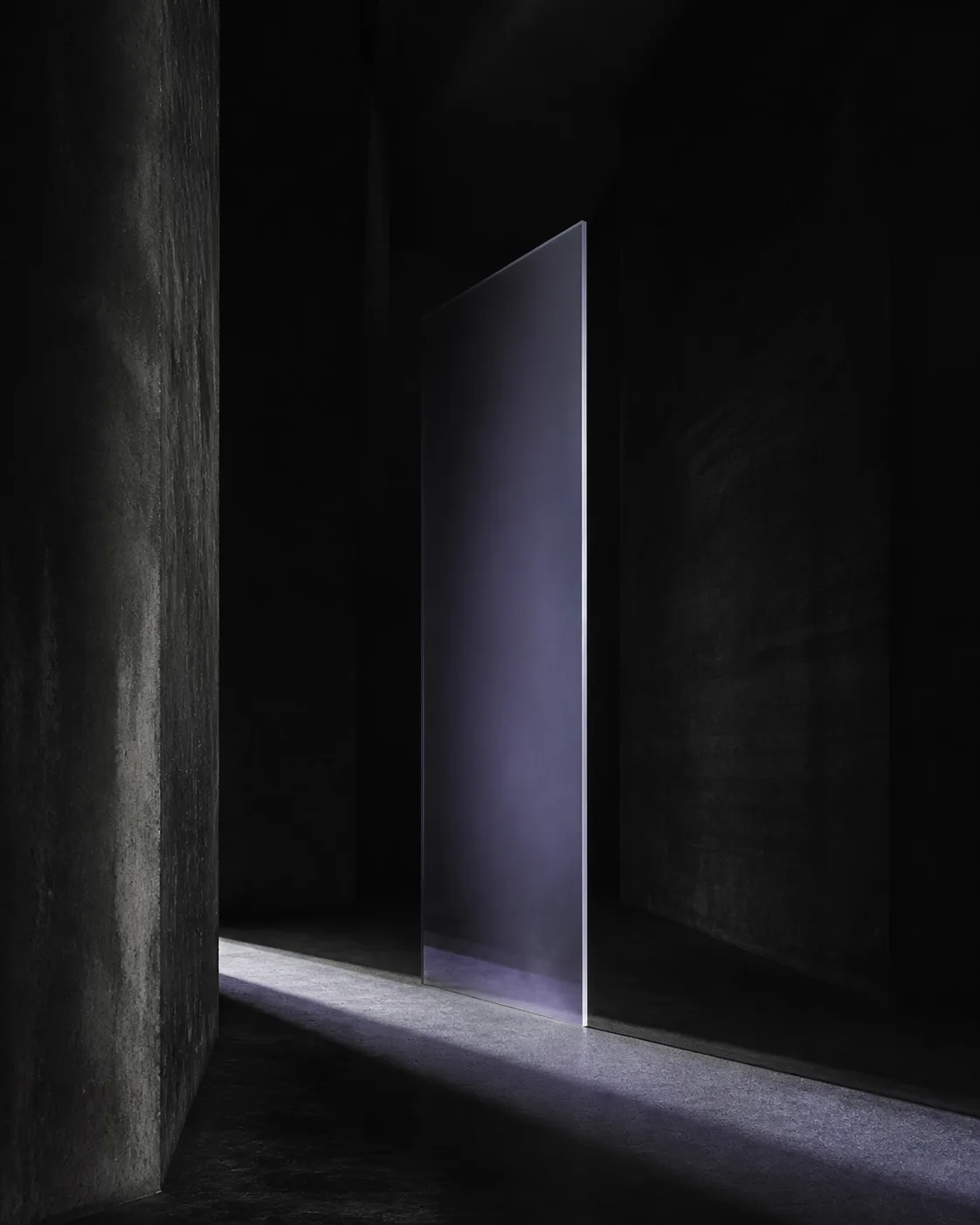 Smoky glass suspended in a dark concrete corridor