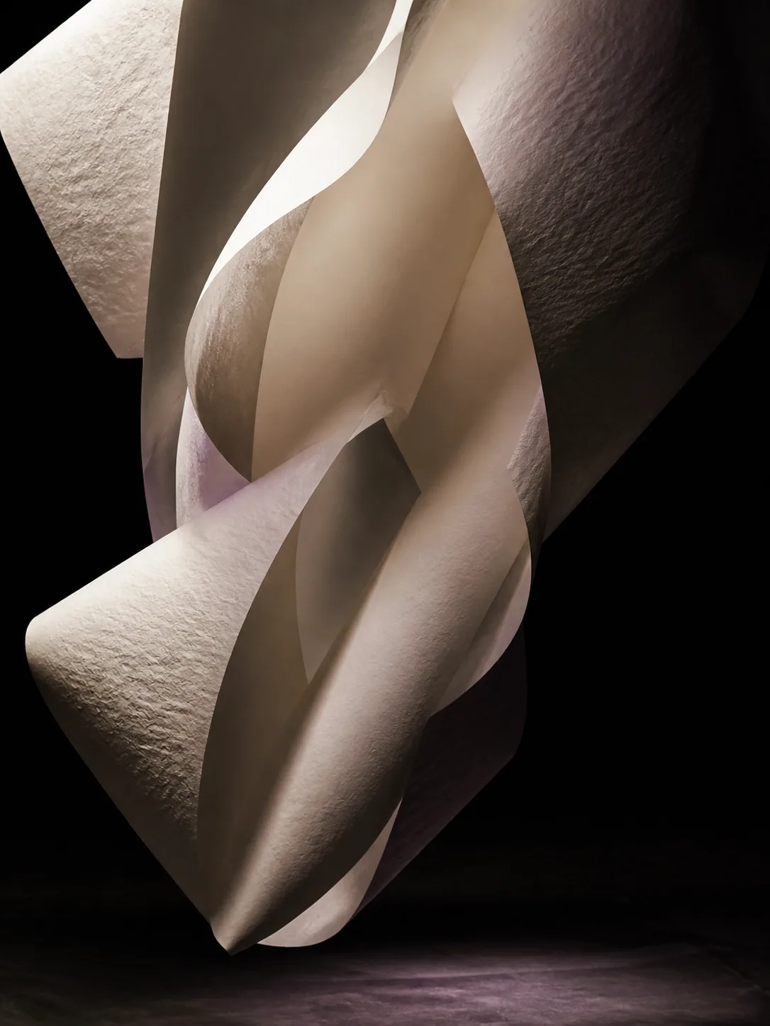 Monumental ivory paper folding through darkness