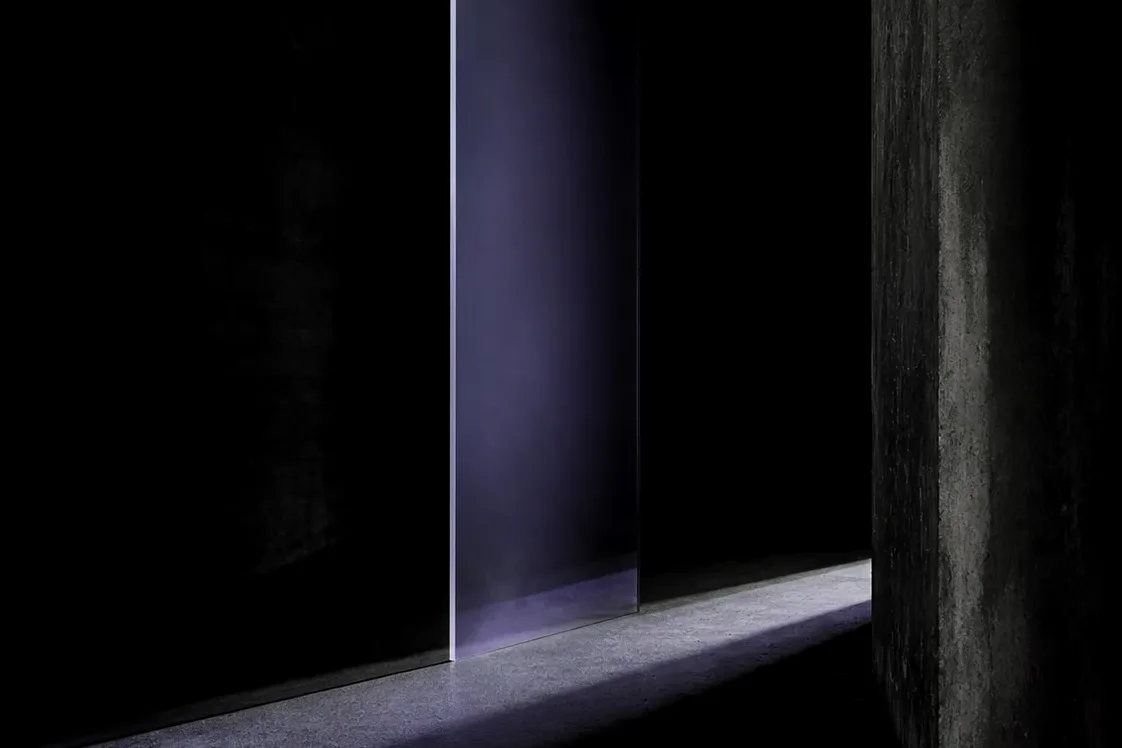 Frosted lilac glass panel casting light across a dark concrete floor